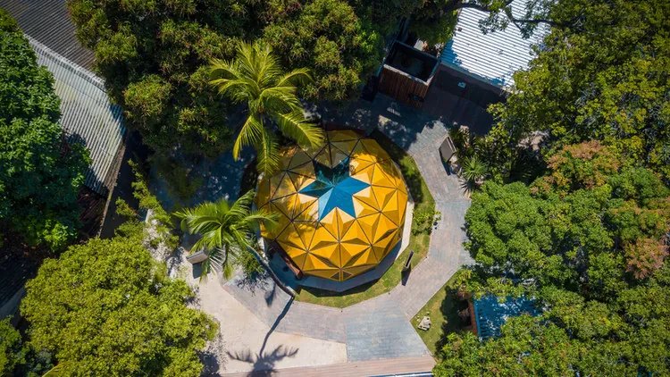 Vista aérea de pavilhão circular com cobertura triangular amarela