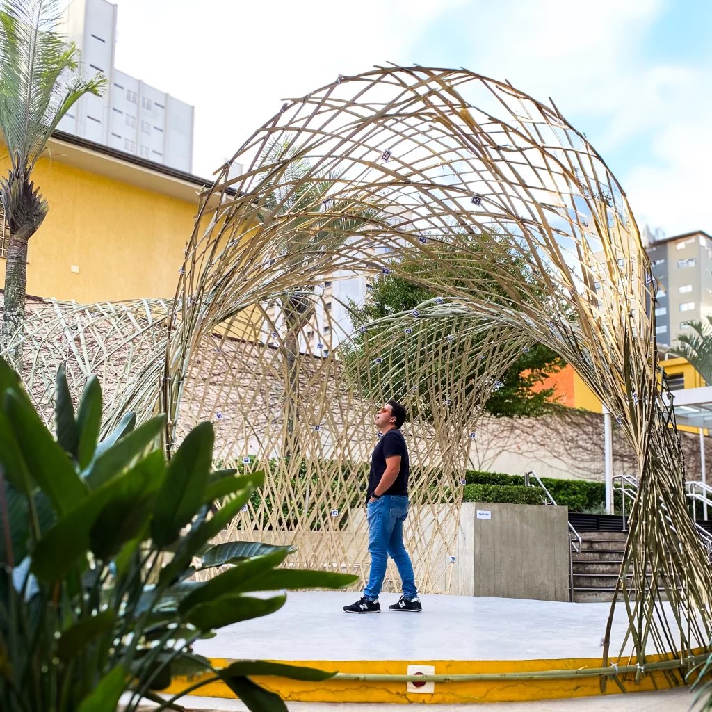 Pavilhão arqueado de bambu com uma pessoa no espaço interno